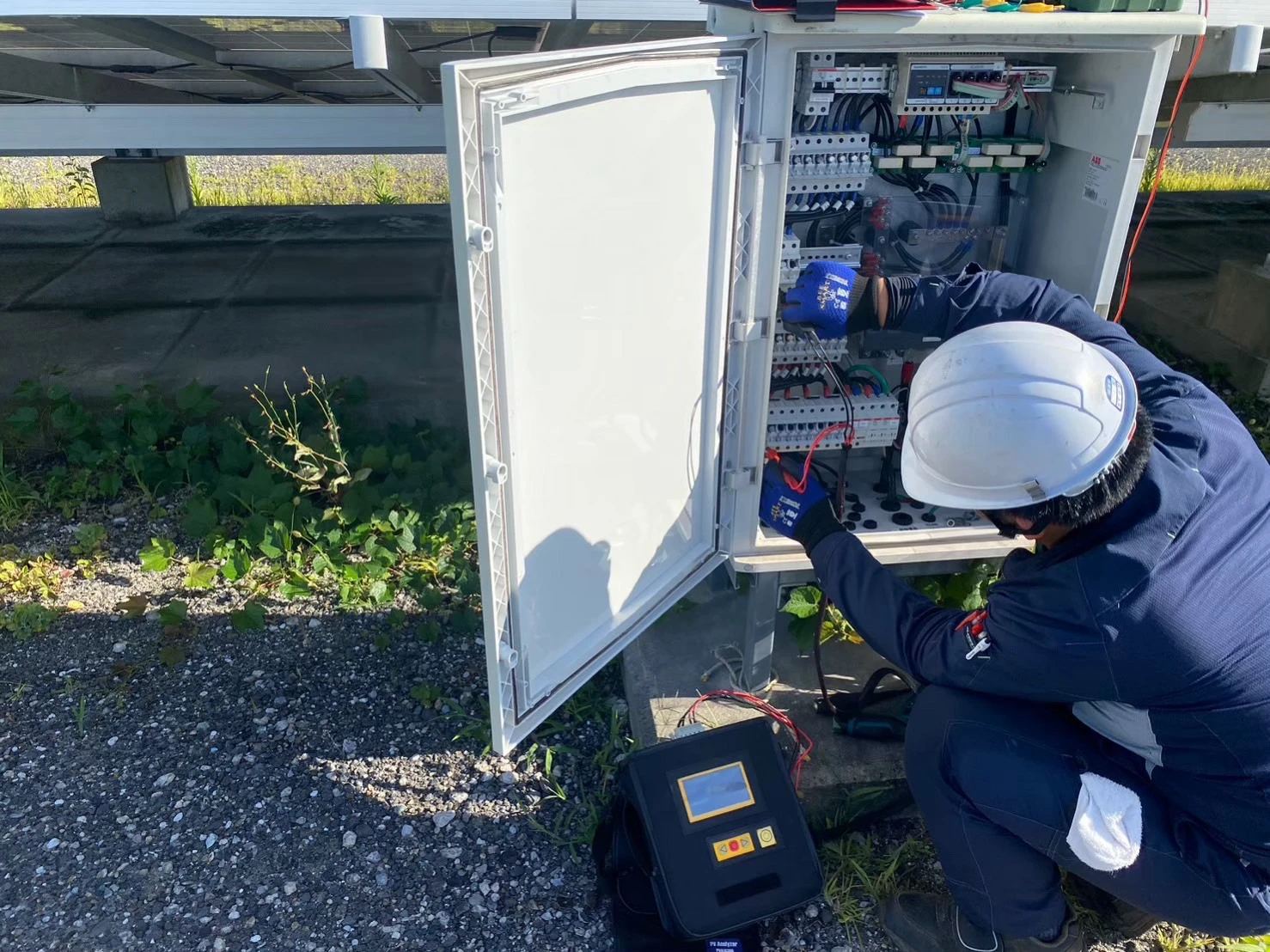 太陽光発電所の接続箱でIVカーブ診断を行う測定作業