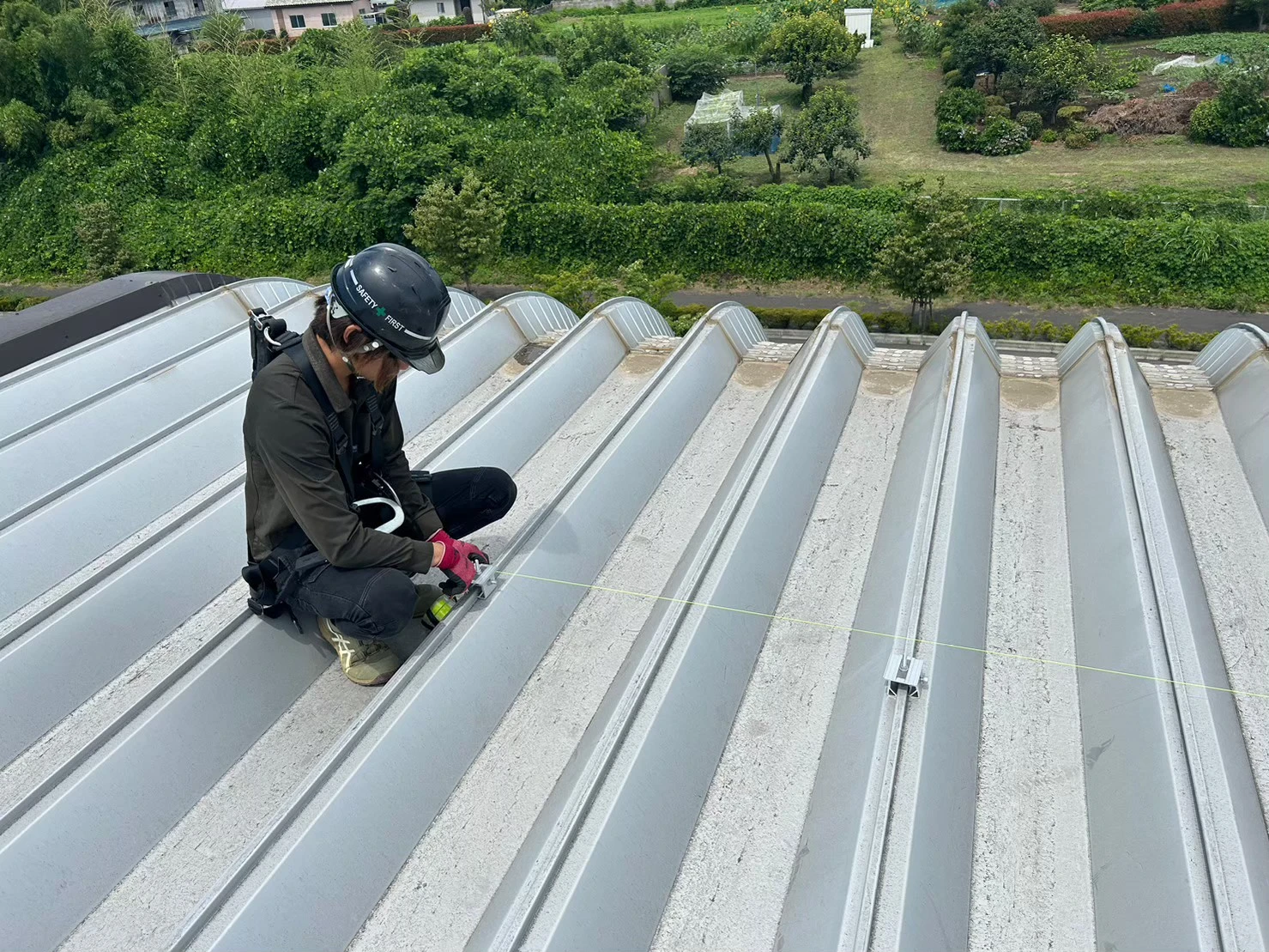 折半屋根上で太陽光パネル固定金具の位置を確認している作業状況